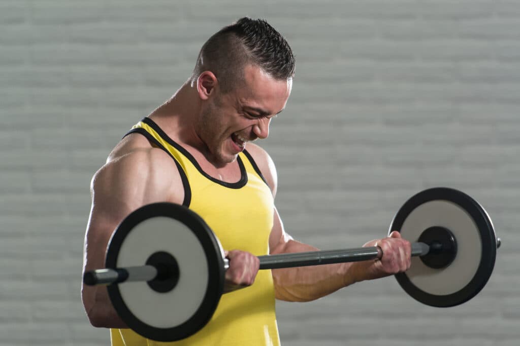 Exercising Biceps With Barbell On White Bricks Background