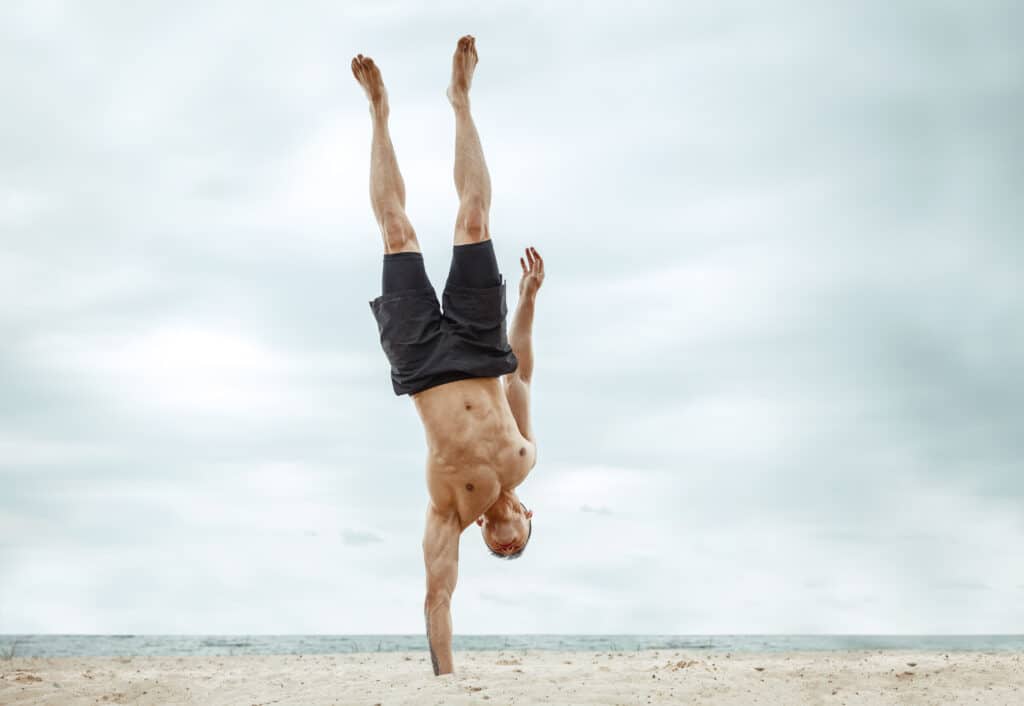 man doing one handed handstand