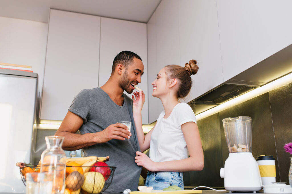 couple flirting in kitchen with healthy food