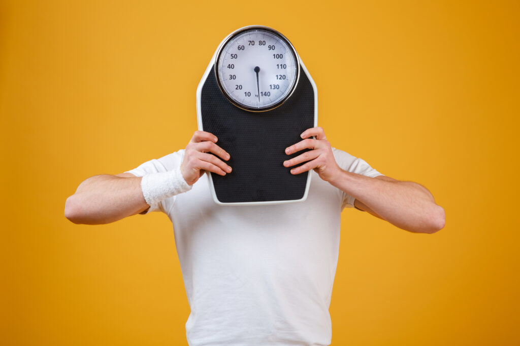 man holding scale in front of his face