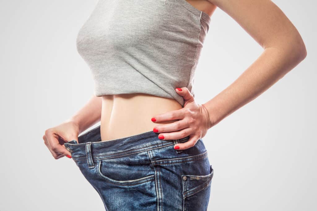 woman checking fit of jeans after losing weight