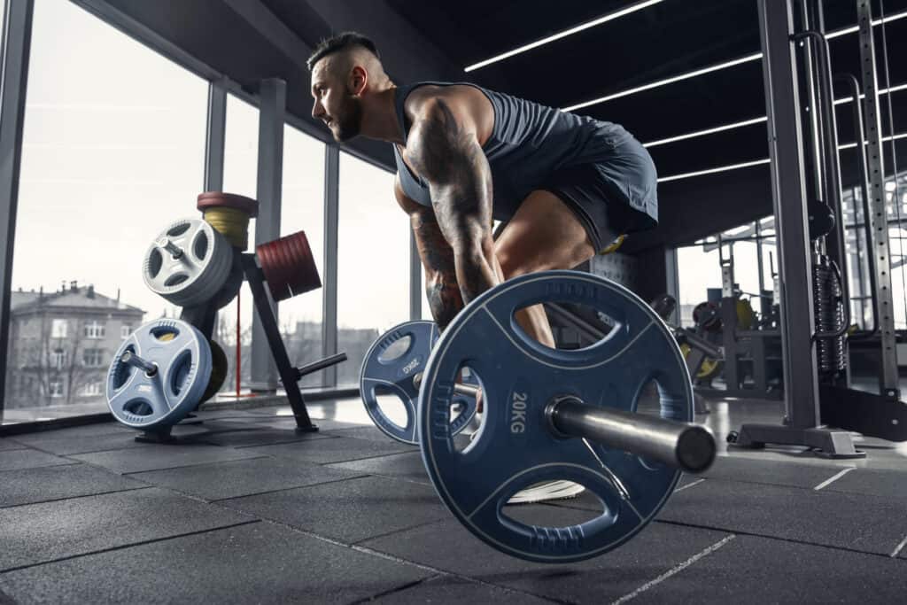 man doing deadlift with barbell at the gym