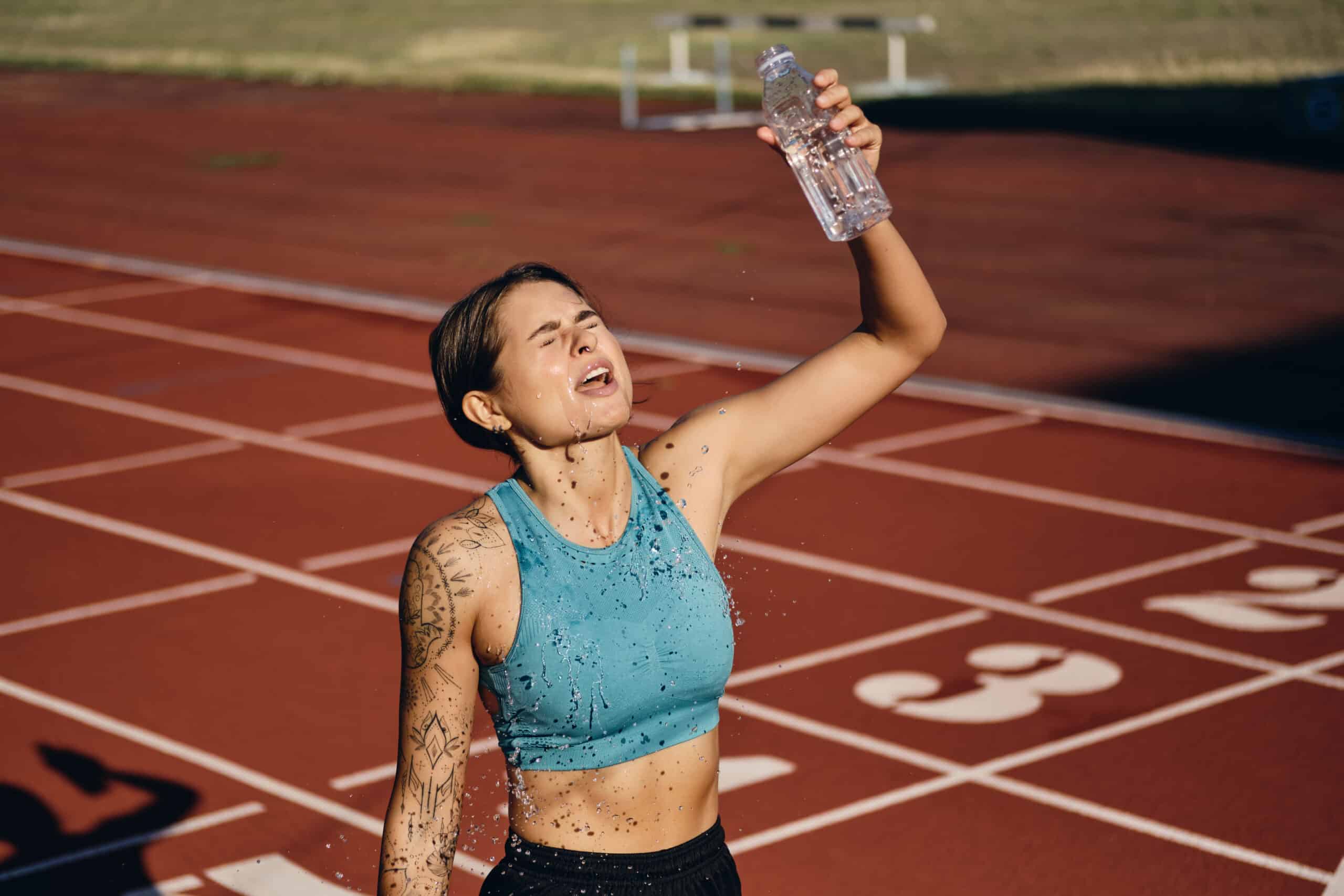 woman pouring fresh water on herself after running a race