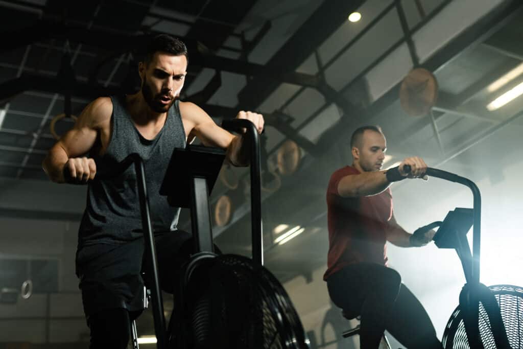 two man using exercise bikes