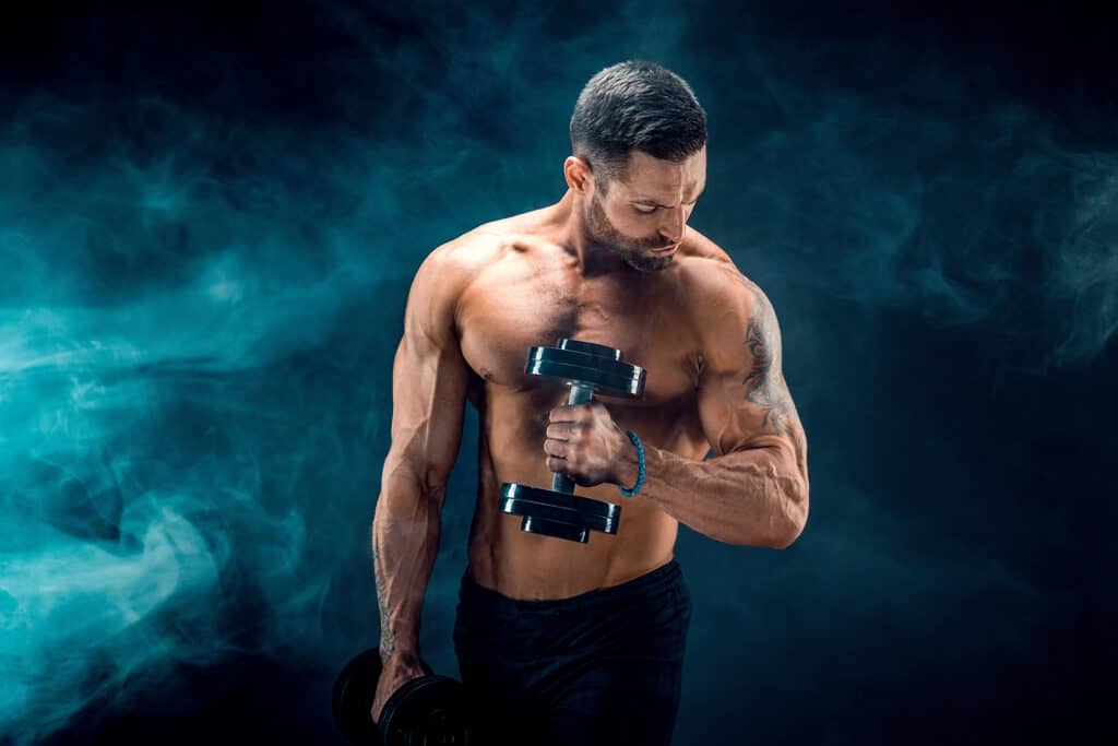 young ripped man lifting dumbbell