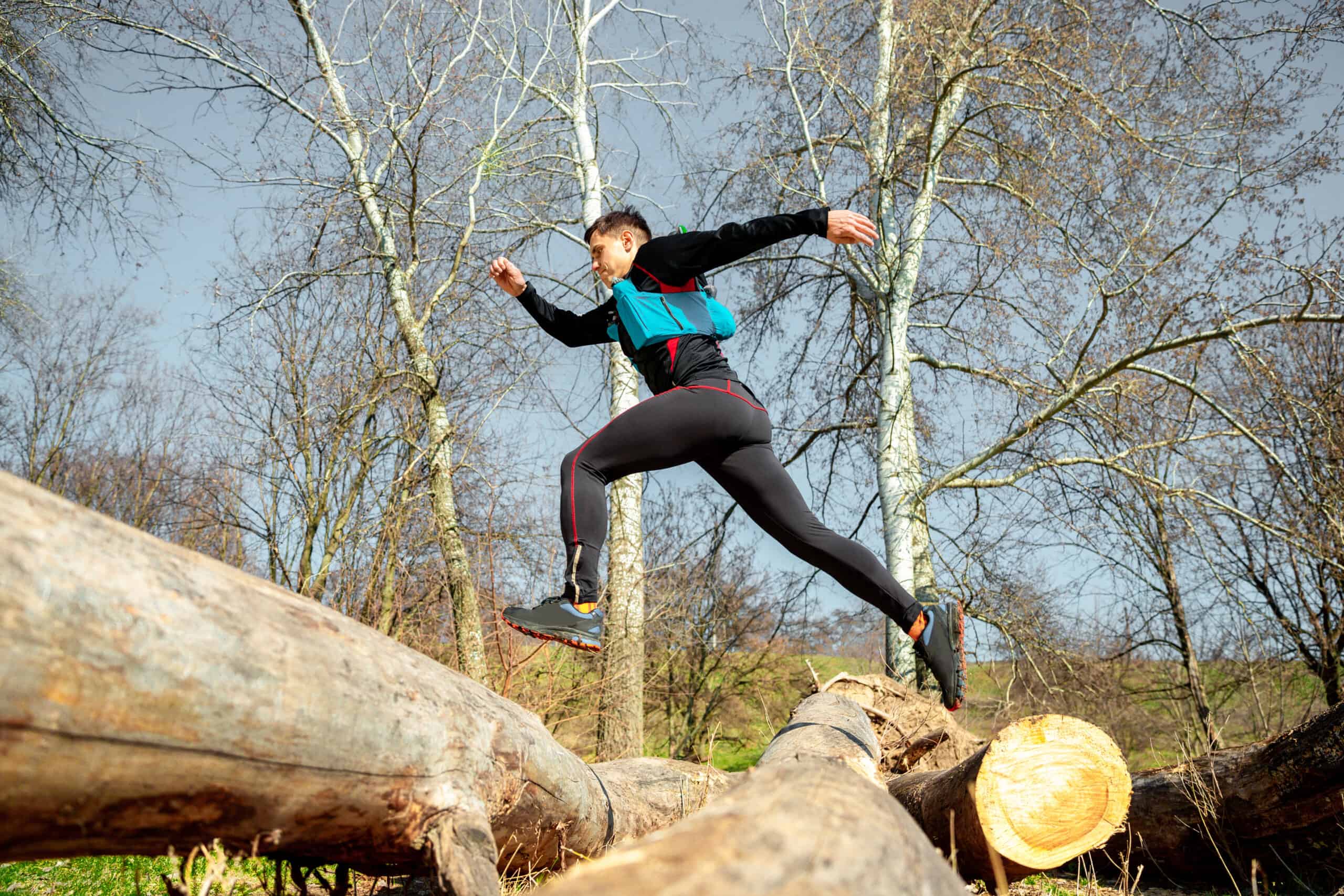 man running over fallen trees