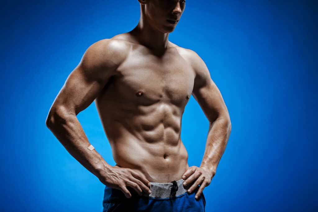 The fit young man with beautiful torso on blue background