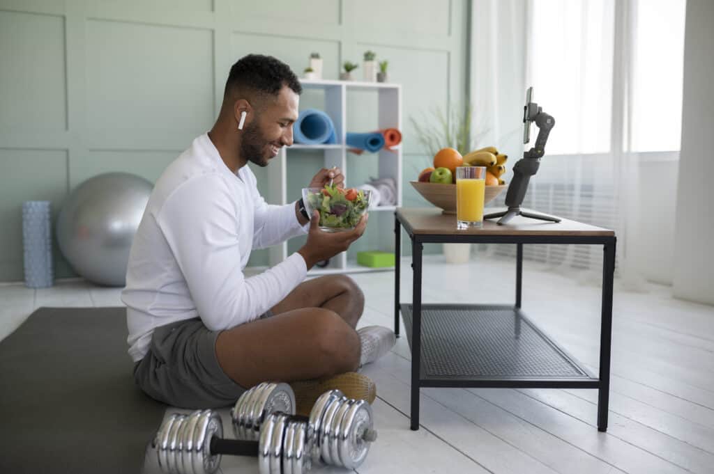 man eating salad next to workout equipment