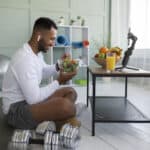 man eating salad next to workout equipment