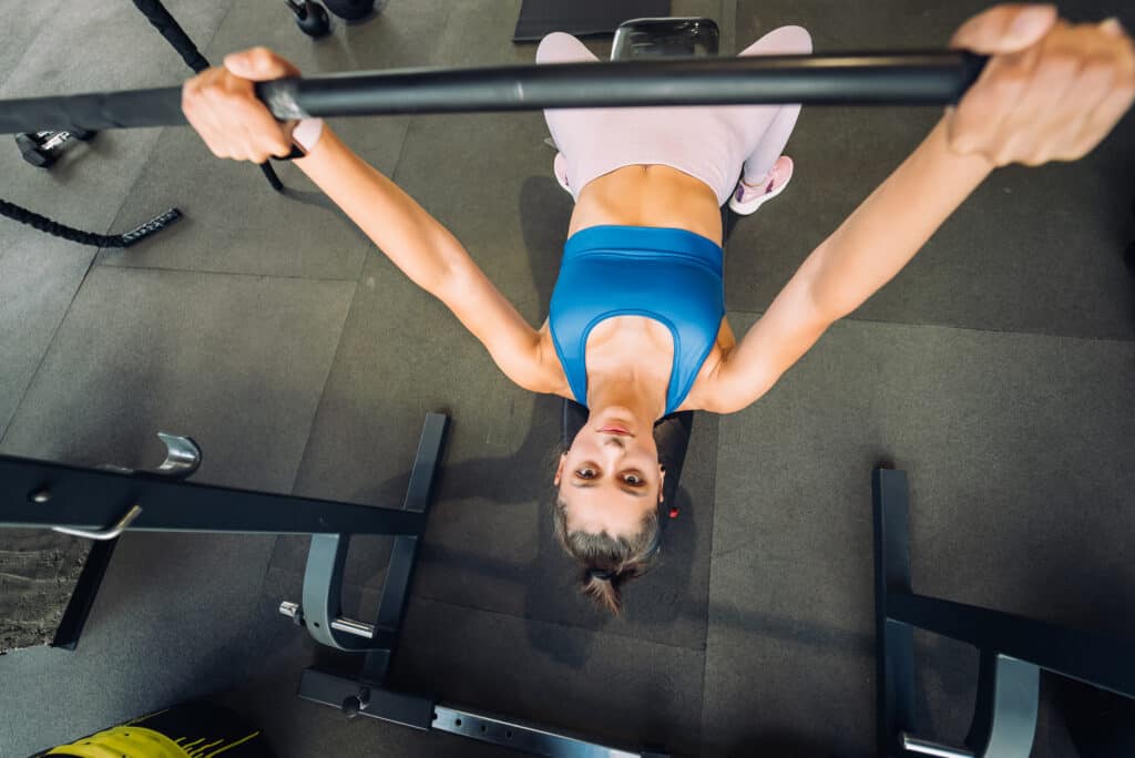 woman performing bench press with a barbell