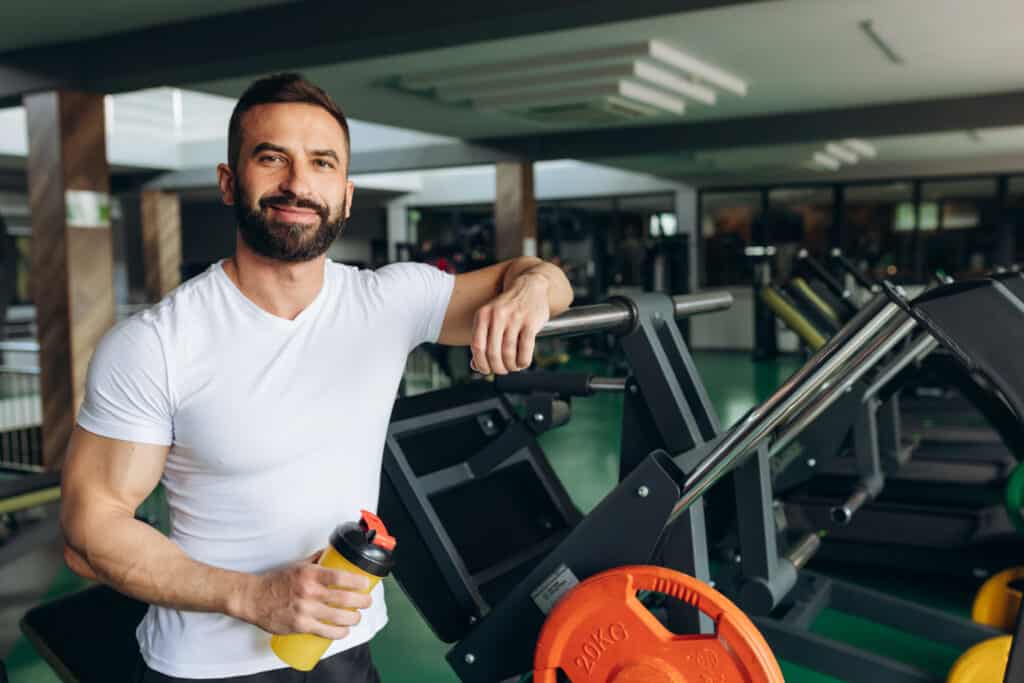 man drinking protein shake during rests at gym