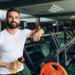 man drinking protein shake during rests at gym