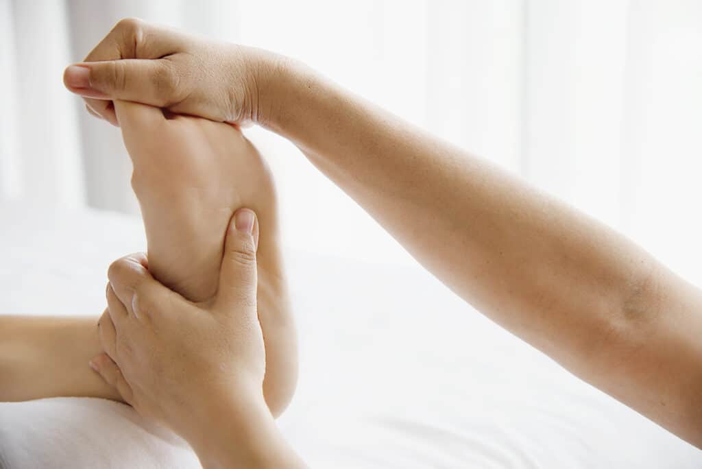 Woman receiving foot massage service from masseuse close up at hand and foot - relax in foot massage therapy service concept